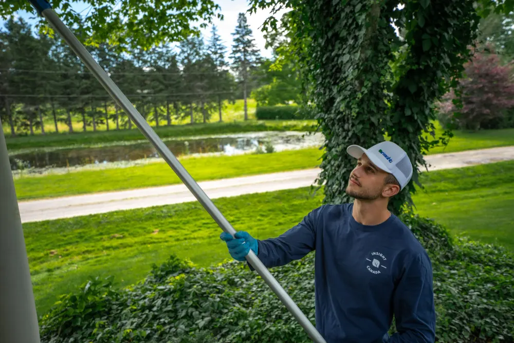 Technicien qui travaille en hauteur avec une perche télescopique le long du toit